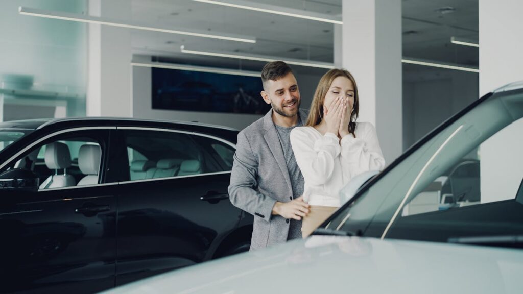 pexels photo 36729867 A joyful couple at a car dealership discovering their new car. Indoor setting, bright lighting.