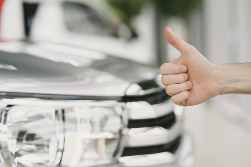 pexels photo 4895414 Close-up of a thumbs up gesture next to a car headlight, symbolizing approval or satisfaction.