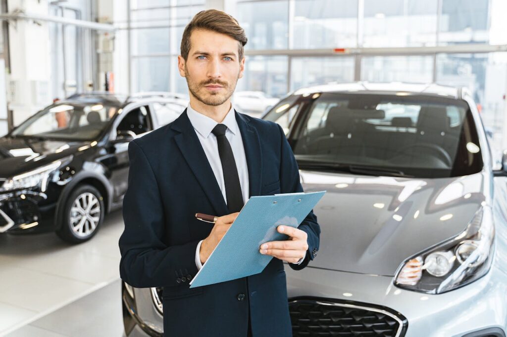 pexels photo 7144184 A confident car salesman in a showroom, holding a clipboard and pen.