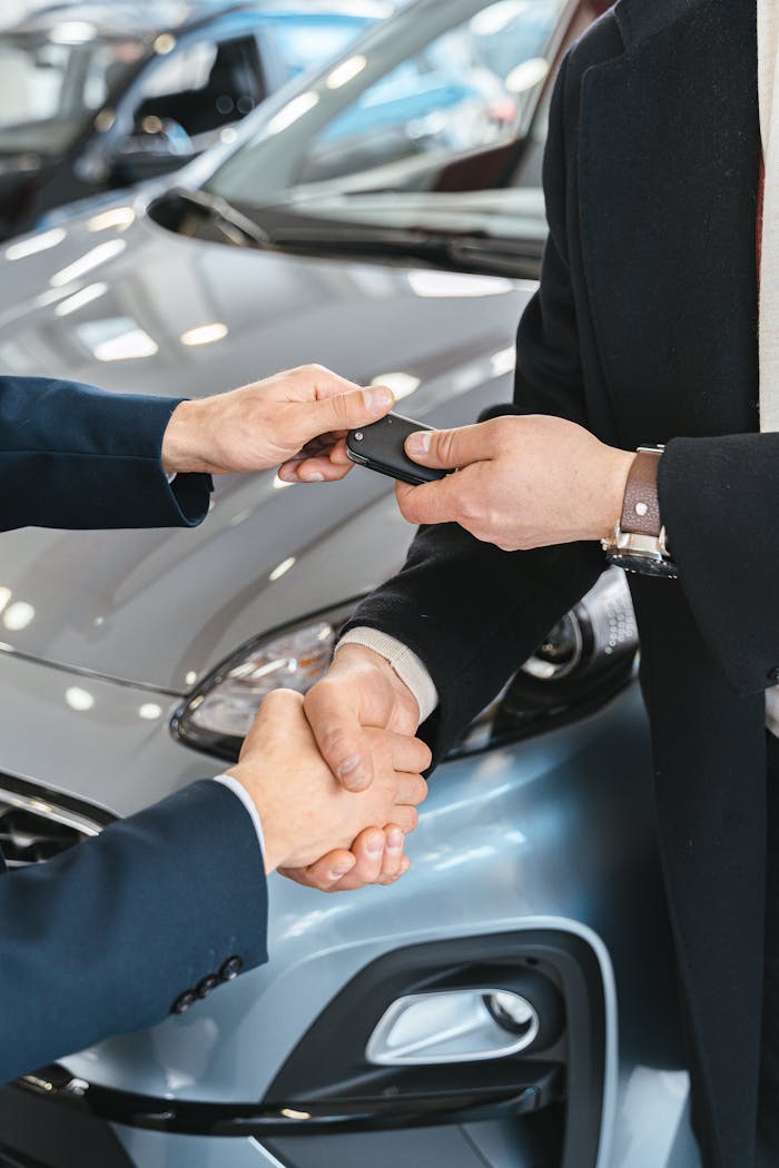 our-story-01 Close-up of a business handshake as car keys are handed over, symbolizing a new car purchase.